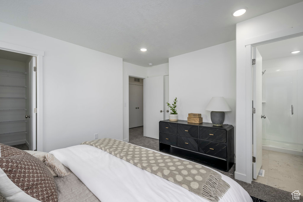 Bedroom featuring a spacious closet, a closet, ensuite bathroom, and light tile flooring