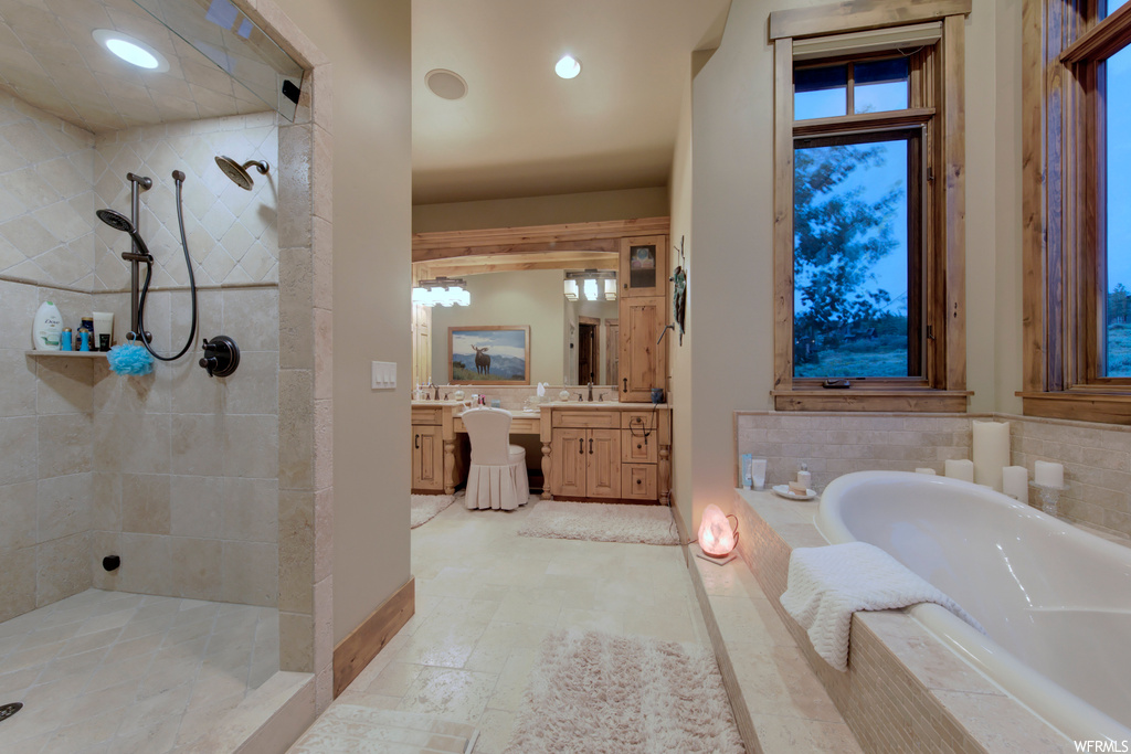 Bathroom featuring separate shower and tub, vanity with extensive cabinet space, mirror, and light tile floors