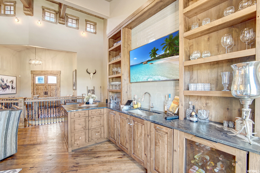 Kitchen featuring plenty of natural light, light hardwood flooring, backsplash, beam ceiling, and a high ceiling