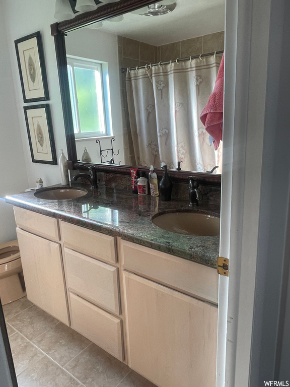 Bathroom featuring light tile flooring, mirror, and double large sink vanity