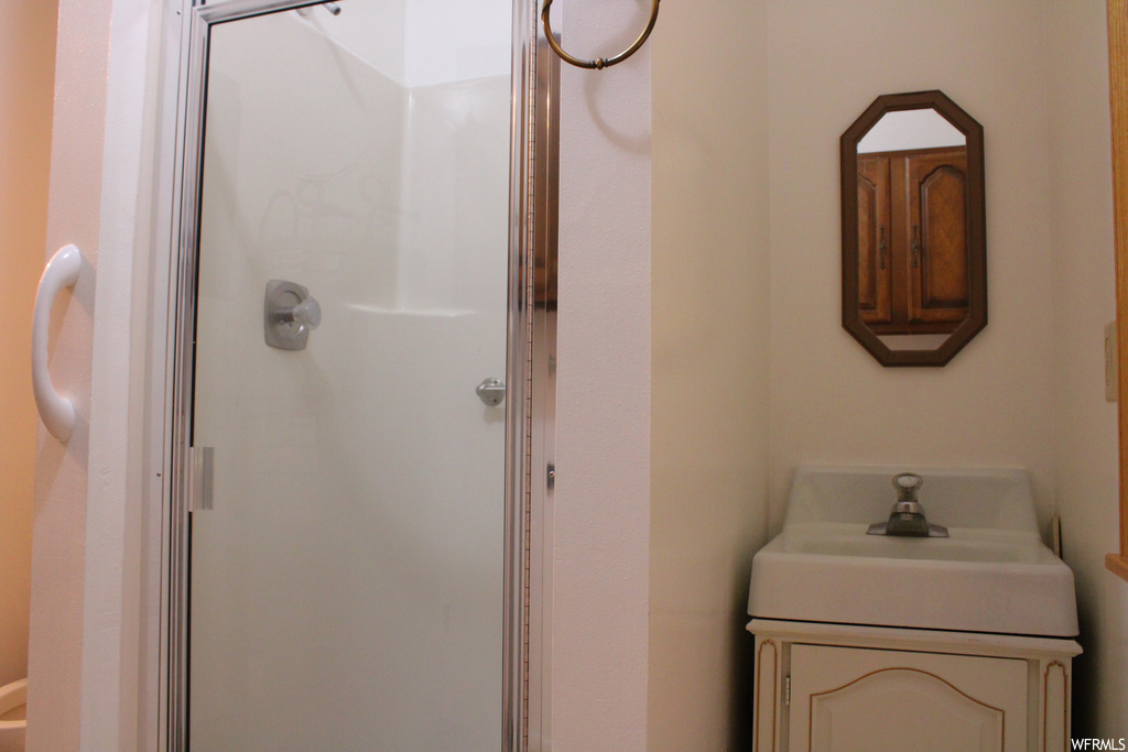 Bathroom featuring large vanity, a shower with shower door, and mirror