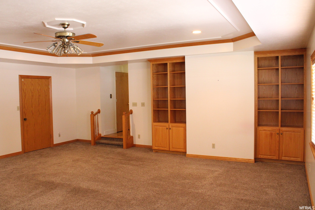 Carpeted empty room with ceiling fan, crown molding, and a raised ceiling
