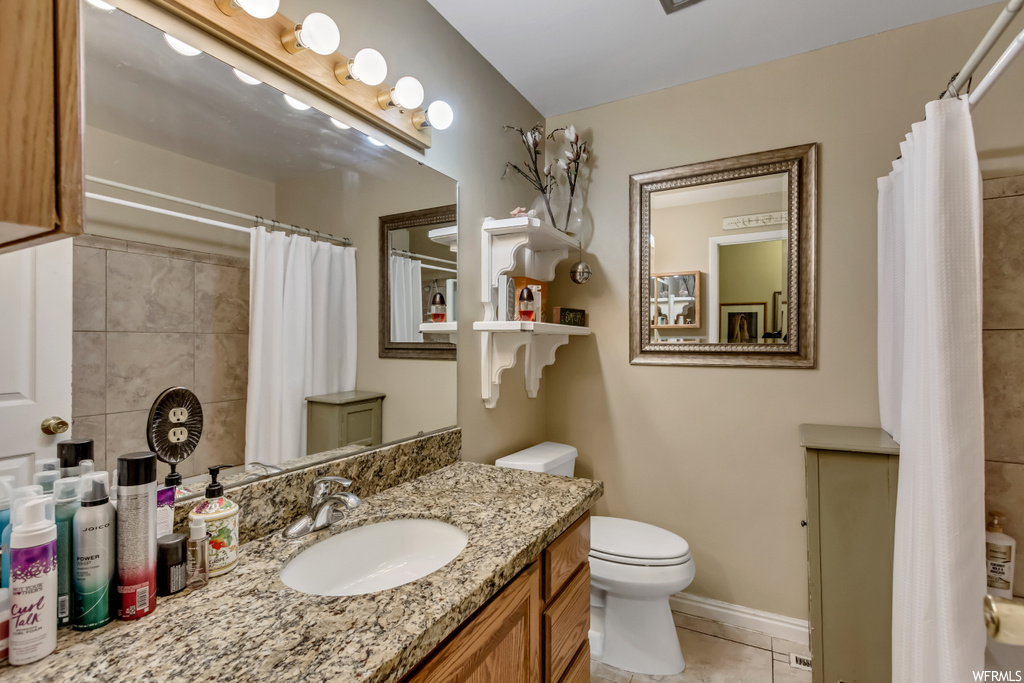 Bathroom with vanity with extensive cabinet space, light tile flooring, and mirror