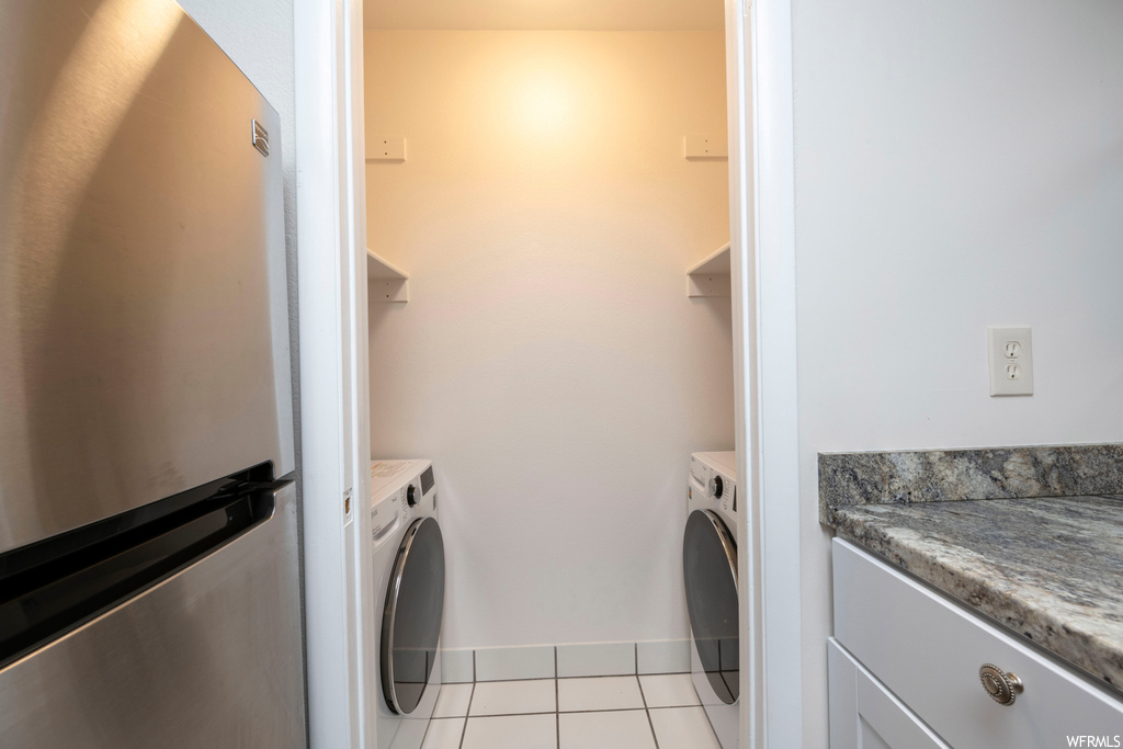 Clothes washing area with washing machine and dryer and light tile floors