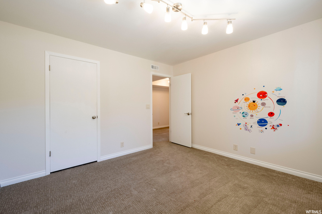 Spare room with light carpet and track lighting