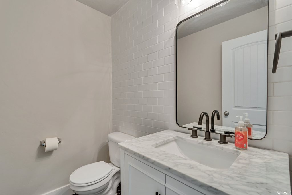 Bathroom featuring large vanity, tile walls, and mirror