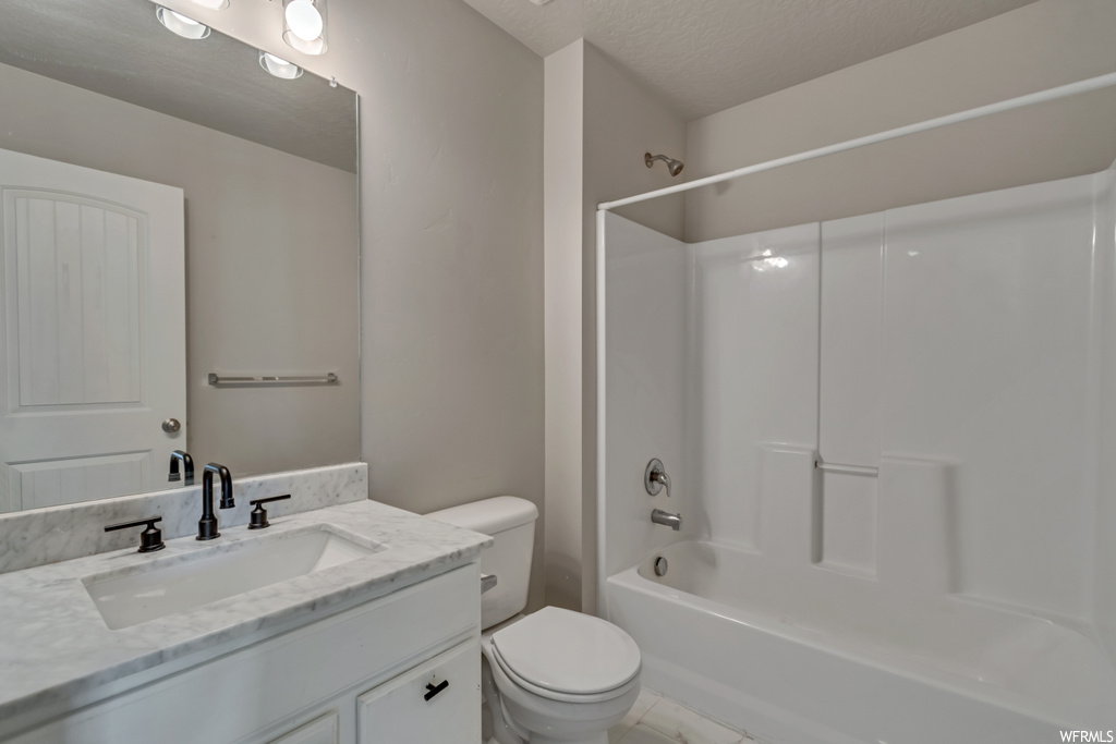 Full bathroom featuring a textured ceiling, shower / bathtub combination, mirror, large vanity, and light tile flooring