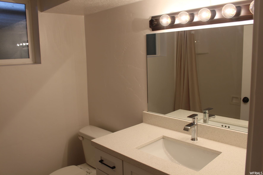 Bathroom with a textured ceiling, mirror, and vanity
