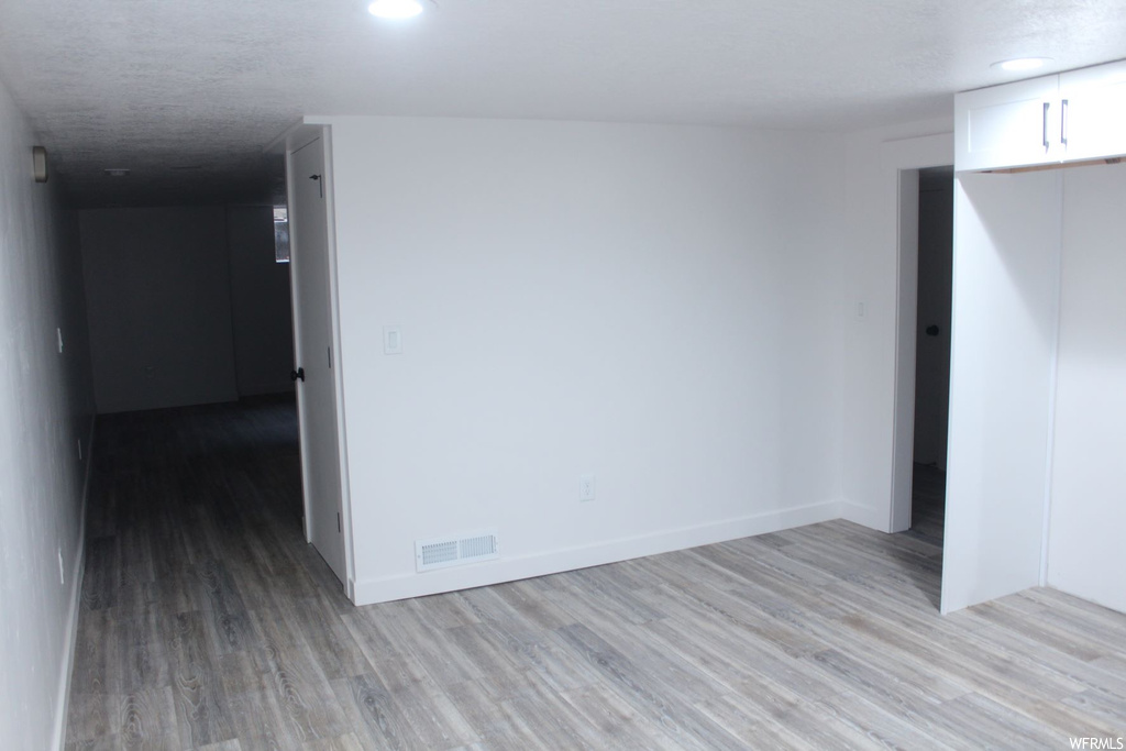 Empty room featuring dark hardwood floors and a textured ceiling