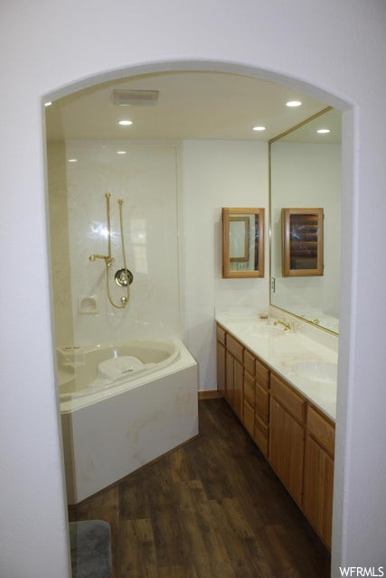 Bathroom featuring dark hardwood flooring, a shower, double vanity, and mirror