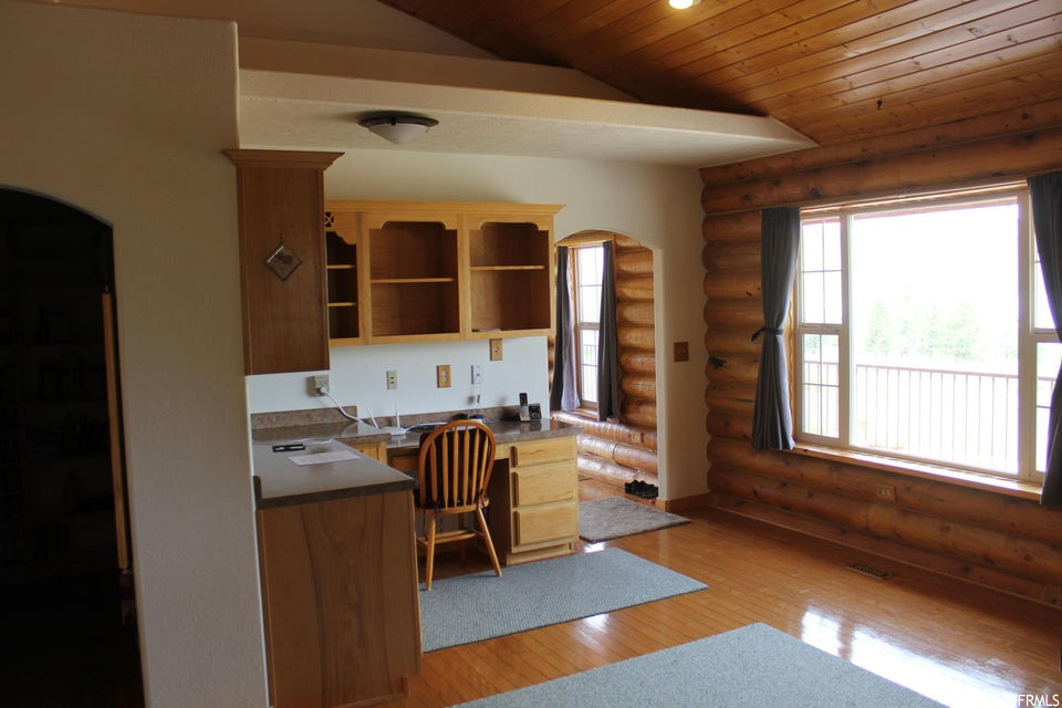 Kitchen with light hardwood flooring, log walls, and vaulted ceiling