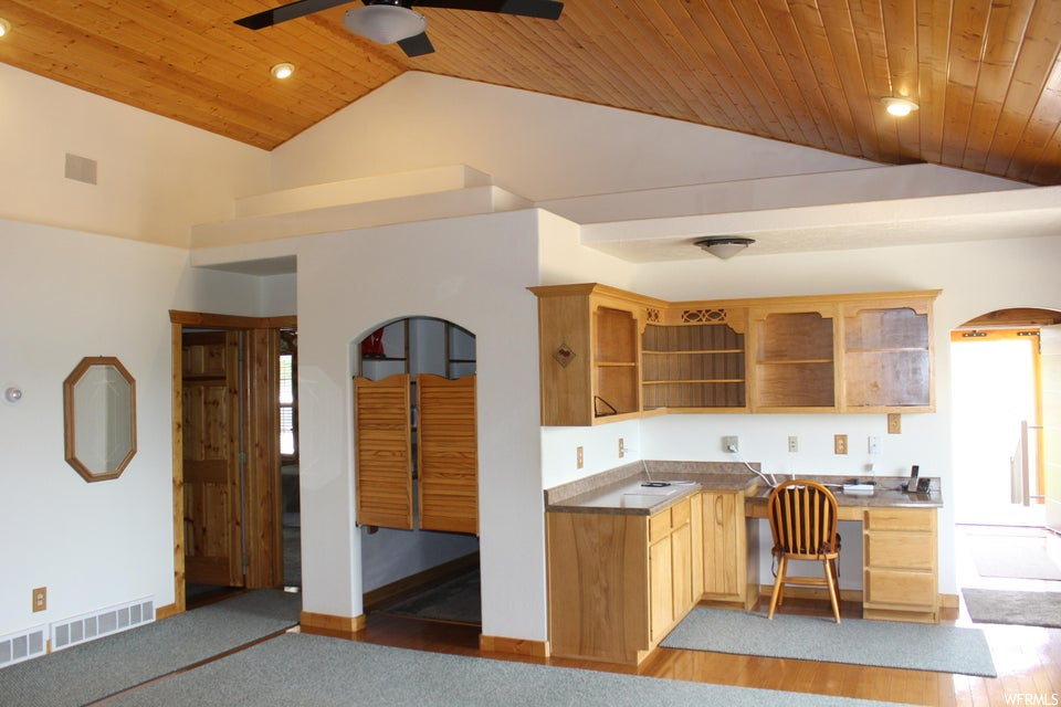 Kitchen featuring wooden ceiling, lofted ceiling, light carpet, brown cabinets, white fridge, a high ceiling, and ceiling fan