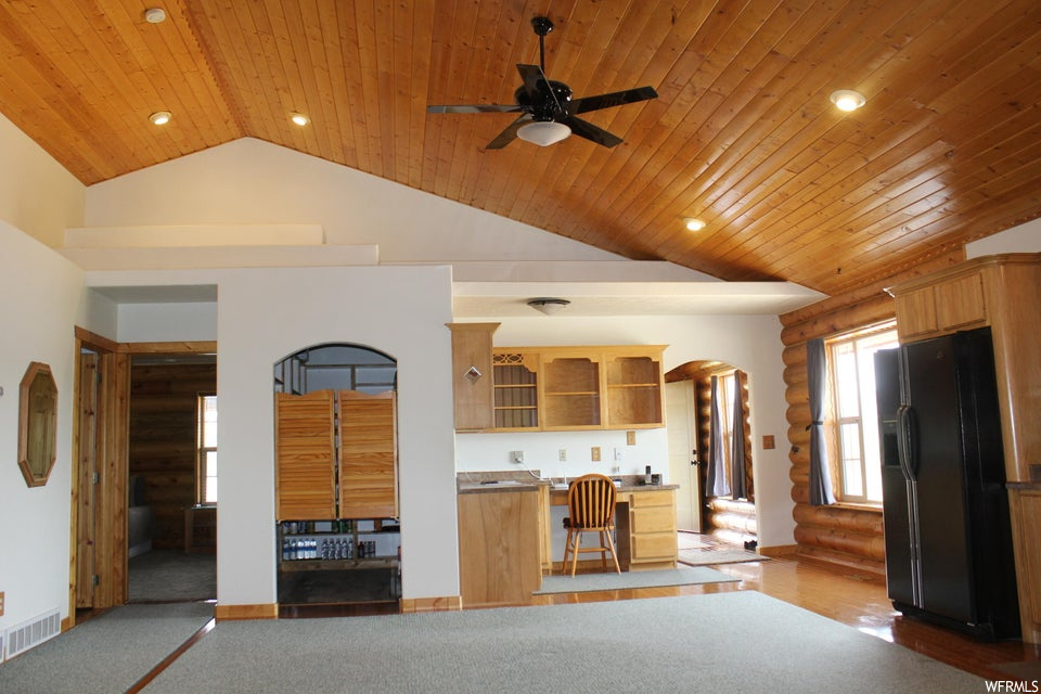 Living room with log walls, wooden ceiling, light carpet, vaulted ceiling, and a high ceiling