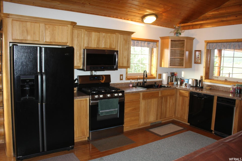 Kitchen featuring black appliances, lofted ceiling, wood ceiling, wood-type flooring, and brown cabinets