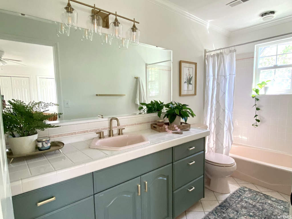 Full bathroom with mirror, light tile floors, shower / tub combo, ceiling fan, vanity, and crown molding