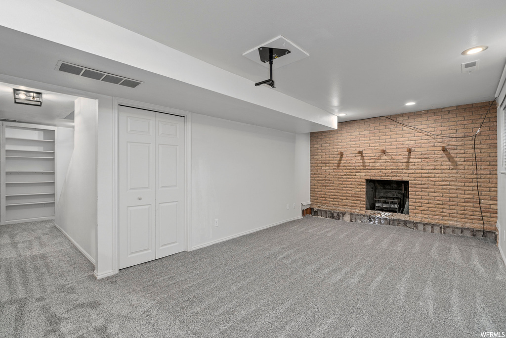 Basement with a fireplace, brick wall, and light carpet