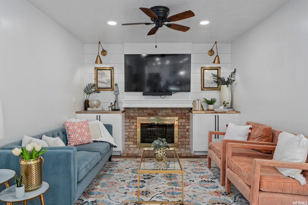 Hardwood floored living room featuring a fireplace and ceiling fan