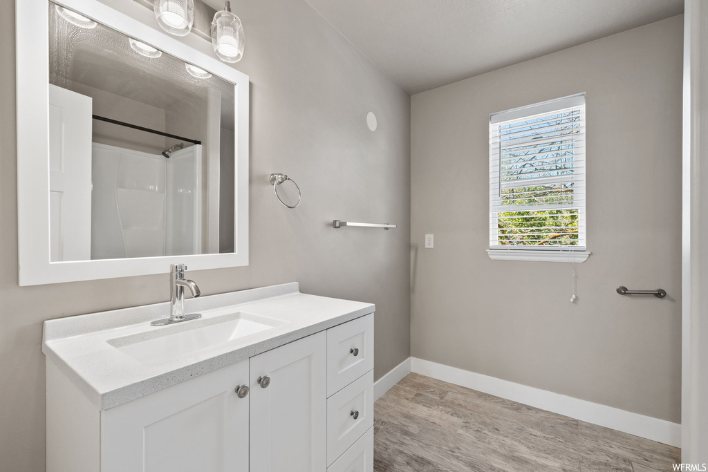 Bathroom featuring large vanity, light hardwood floors, and mirror