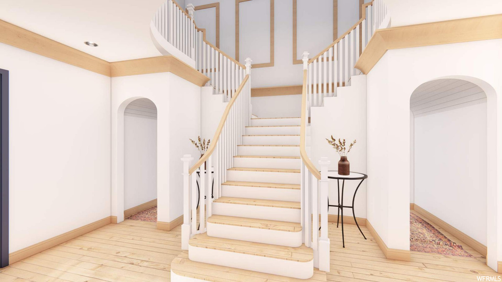 Stairway with light hardwood floors and a high ceiling