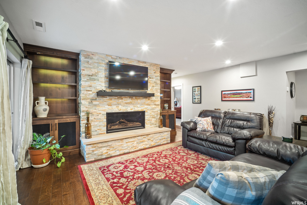 Living room with a fireplace, dark hardwood flooring, and built in shelves