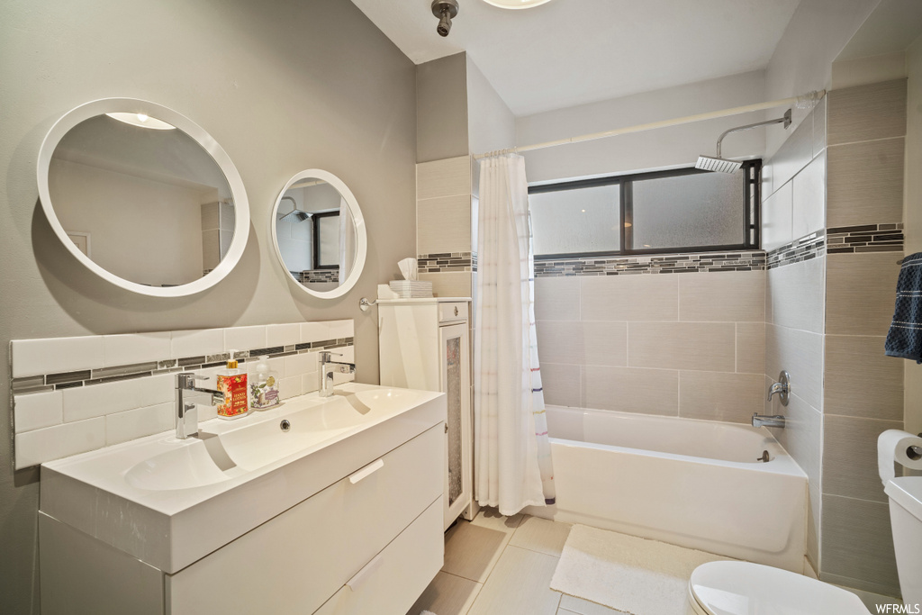 Full bathroom featuring tile flooring, toilet, tasteful backsplash, oversized vanity, and shower / bath combo
