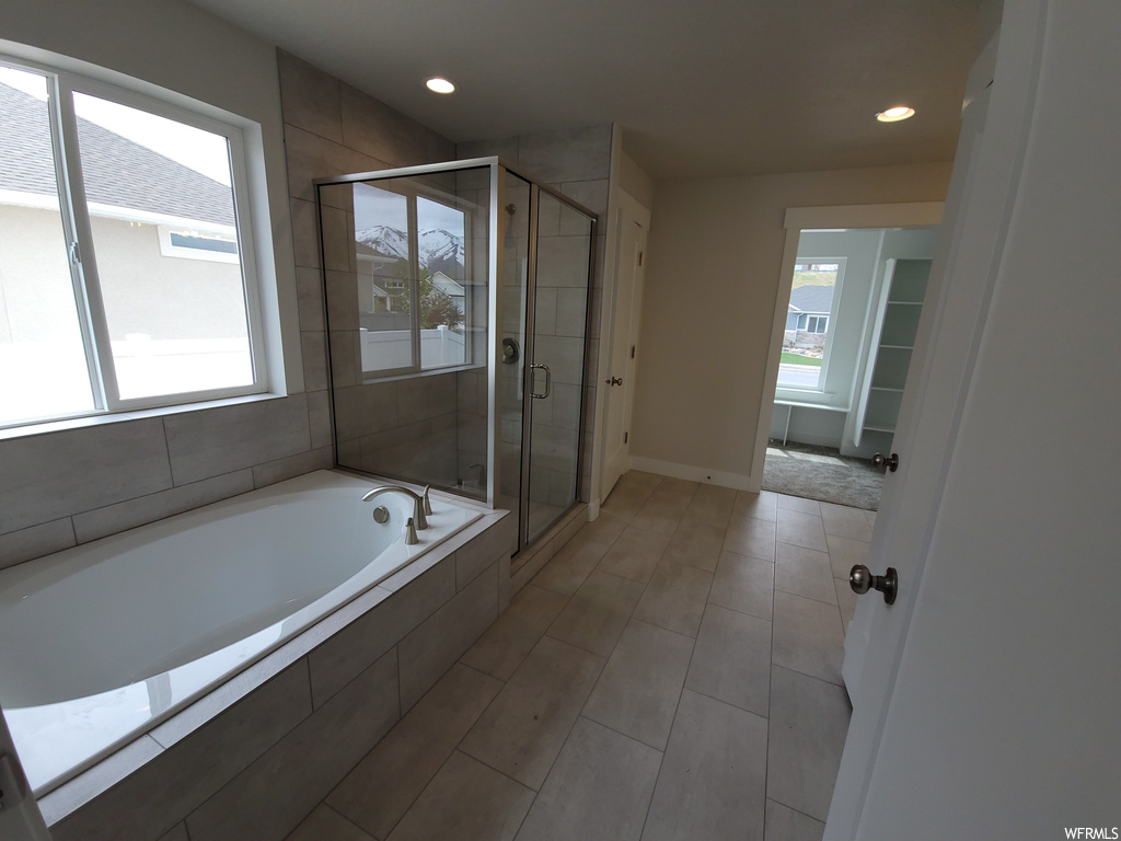 Bathroom with shower with separate bathtub, plenty of natural light, and light tile flooring