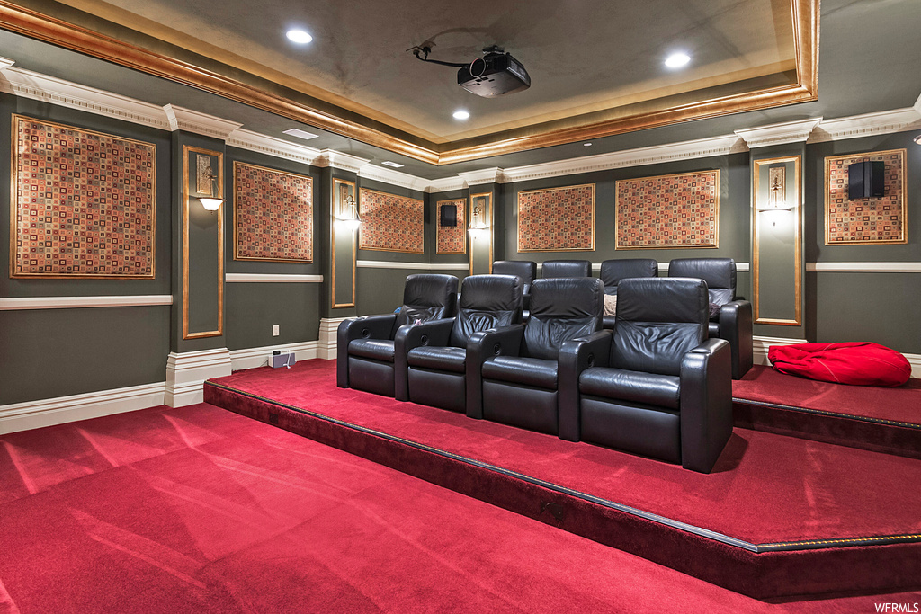 Carpeted home theater featuring crown molding and a tray ceiling