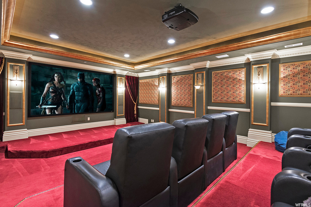 Carpeted cinema featuring ornamental molding and a raised ceiling