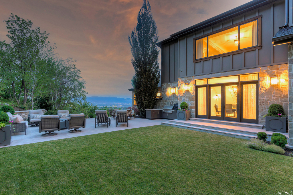 Yard at dusk featuring a mountain view, an outdoor living space, and a patio