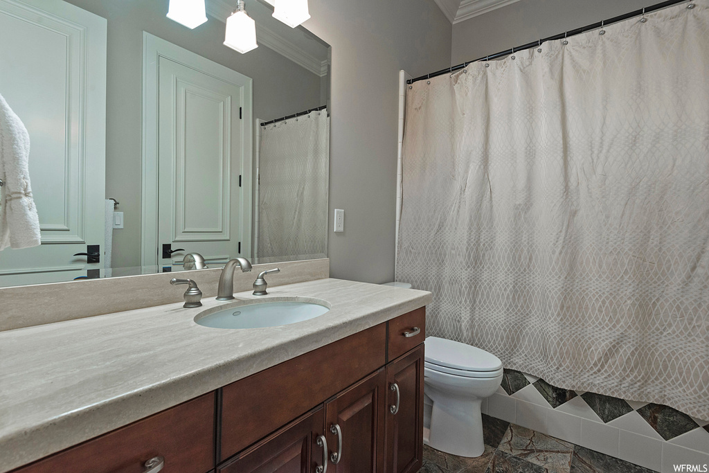 Bathroom featuring tile flooring, large vanity, mirror, and crown molding
