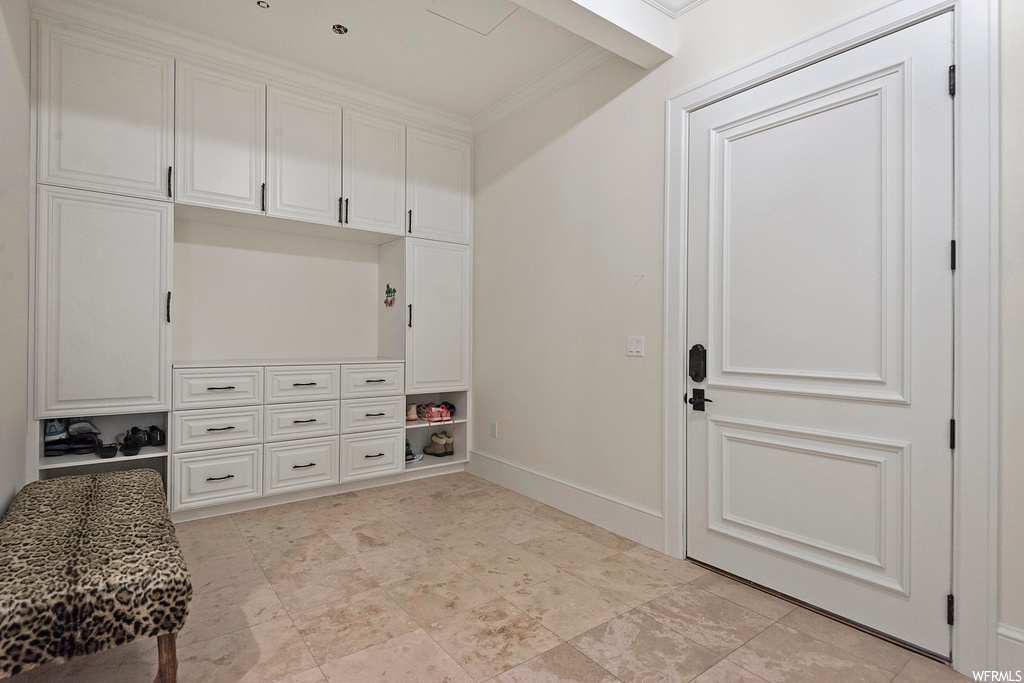 Mudroom featuring ornamental molding and light tile floors