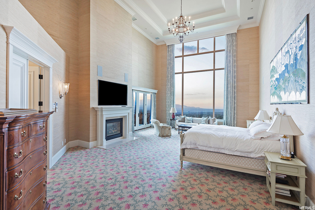 Bedroom featuring a chandelier, light carpet, ornamental molding, a high ceiling, and a raised ceiling