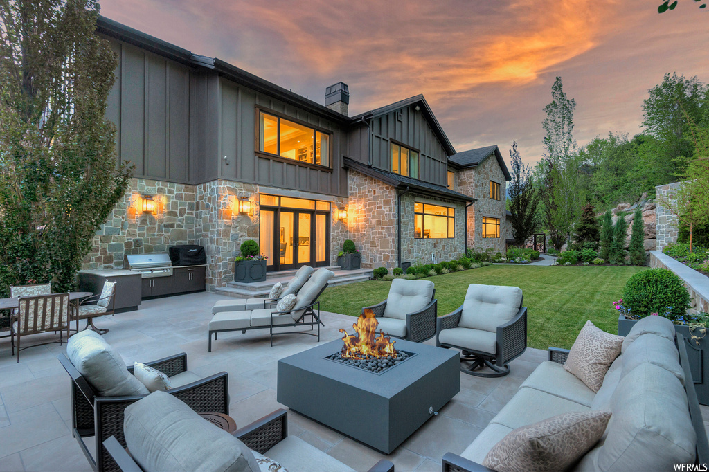 Patio terrace at dusk with a yard and an outdoor living space with a fire pit
