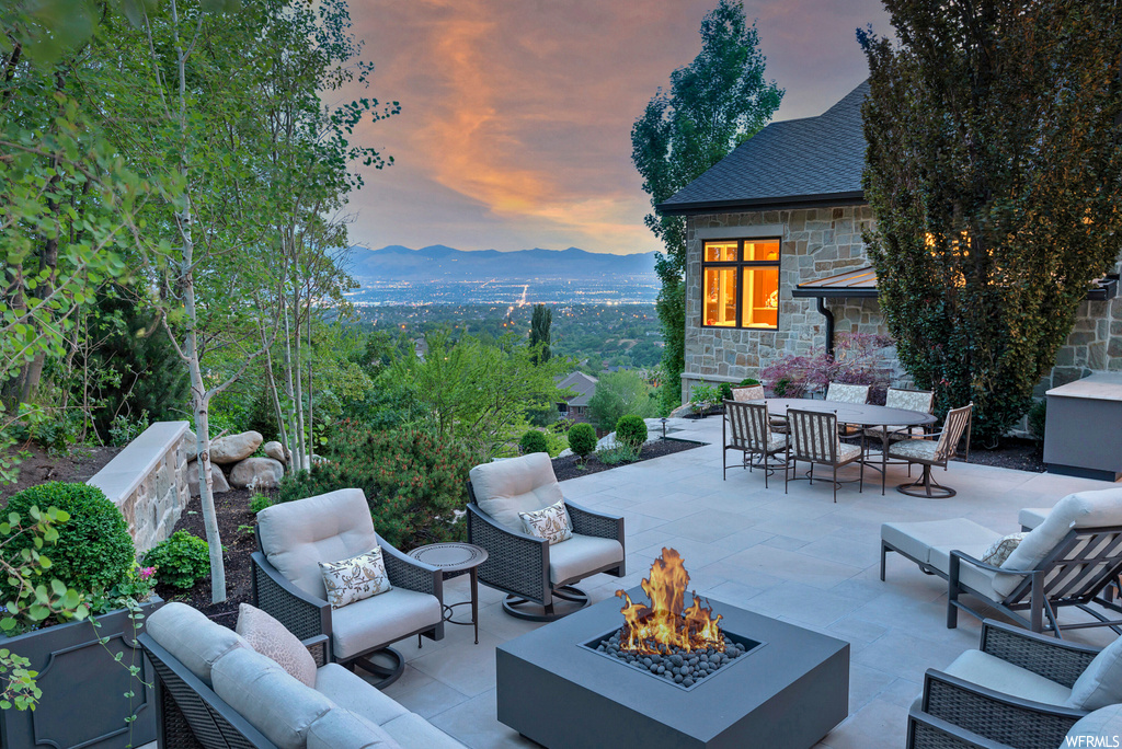 Patio terrace at dusk featuring a mountain view and an outdoor living space with a fire pit