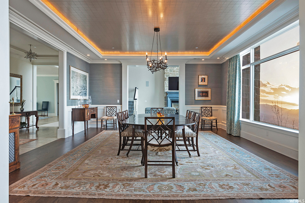 Wood floored dining area with a notable chandelier and a tray ceiling