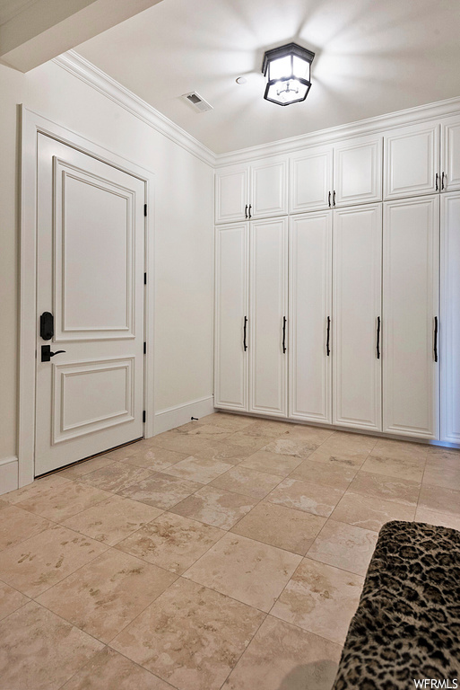 Interior space featuring ornamental molding and light tile flooring
