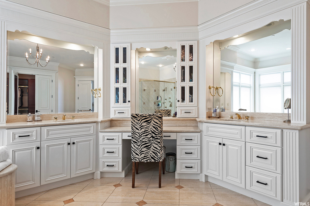 Bathroom featuring a shower with shower door, mirror, crown molding, dual large vanity, and light tile flooring