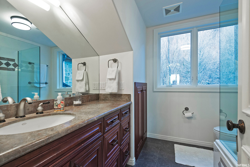 Bathroom with vanity, tile flooring, mirror, and lofted ceiling