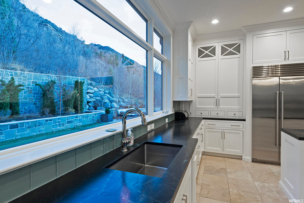 Kitchen with stainless steel built in fridge, light tile flooring, white cabinets, a wealth of natural light, and backsplash