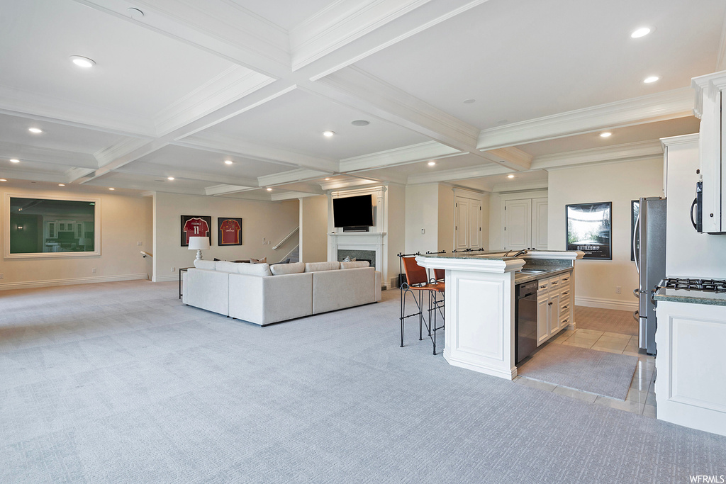 Kitchen featuring beamed ceiling, light countertops, light carpet, coffered ceiling, black appliances, and a fireplace