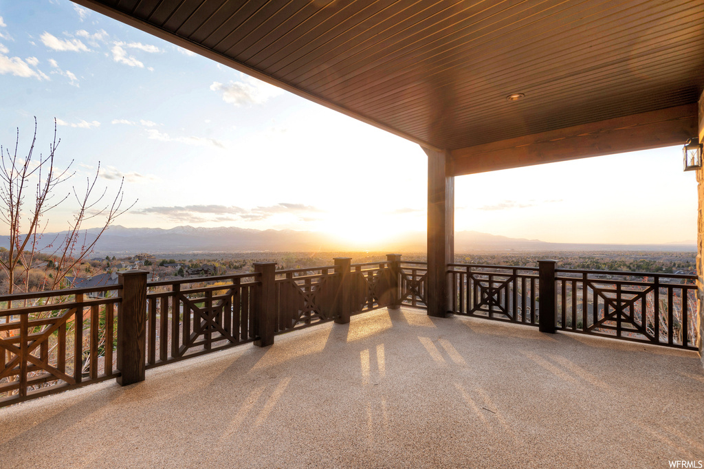 Patio terrace at dusk featuring balcony and a mountain view