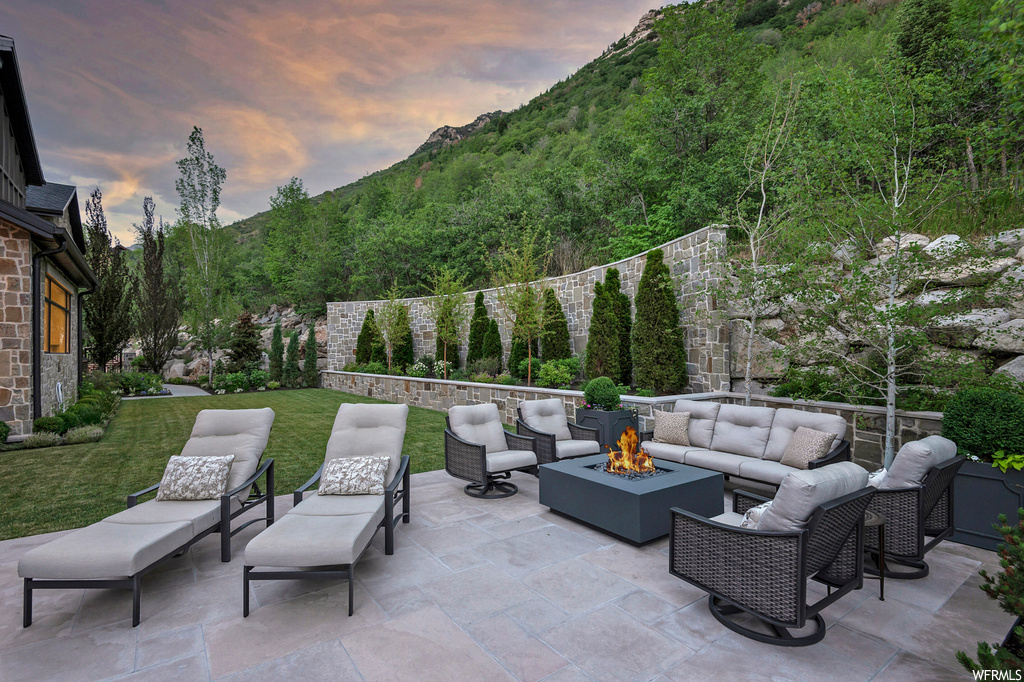 Patio terrace at dusk featuring a yard and an outdoor living space with a fire pit