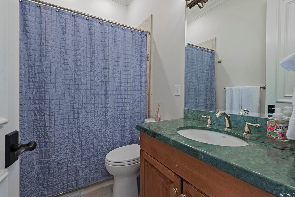 Bathroom featuring tile flooring, mirror, crown molding, and vanity