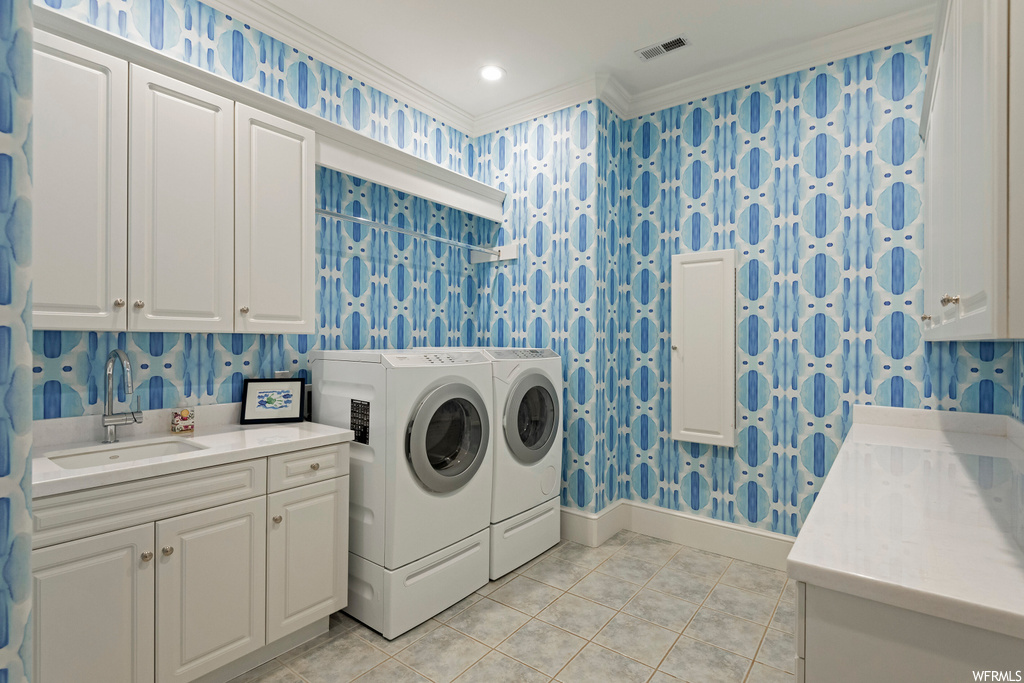Laundry room featuring crown molding, light tile flooring, and washer and clothes dryer