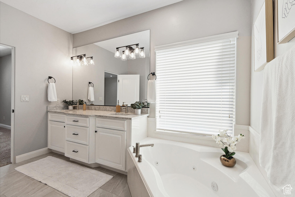 Bathroom with double sink vanity, a relaxing tiled bath, and tile floors