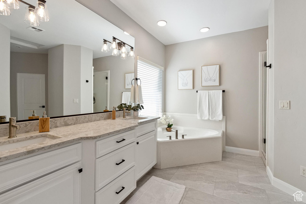 Bathroom with tile flooring, a notable chandelier, shower with separate bathtub, and dual vanity