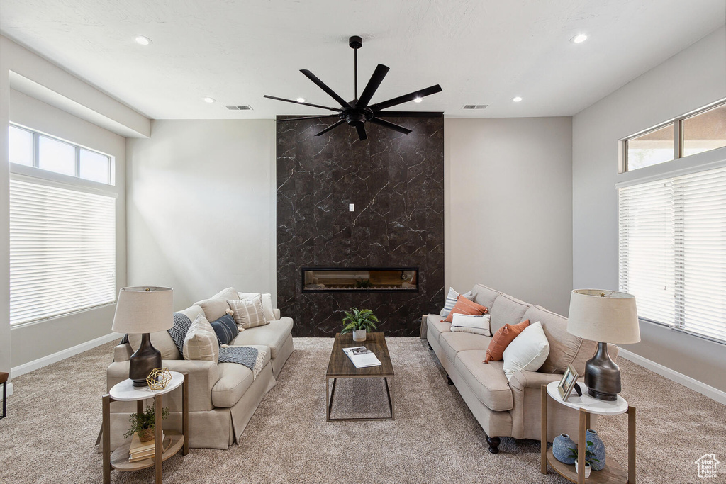 Living room featuring ceiling fan, light colored carpet, and a premium fireplace