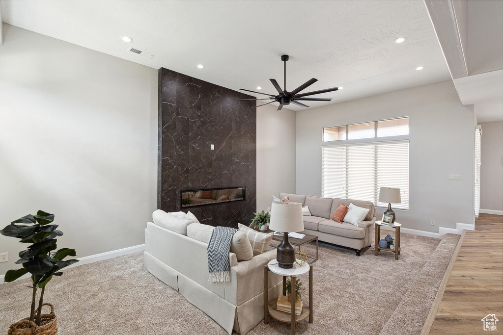 Living room featuring ceiling fan, a high end fireplace, and light hardwood / wood-style flooring