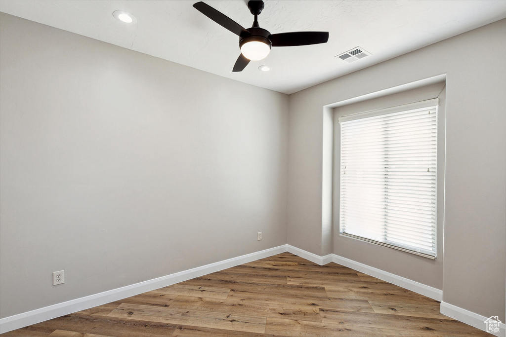 Unfurnished room featuring ceiling fan, a wealth of natural light, and wood-type flooring