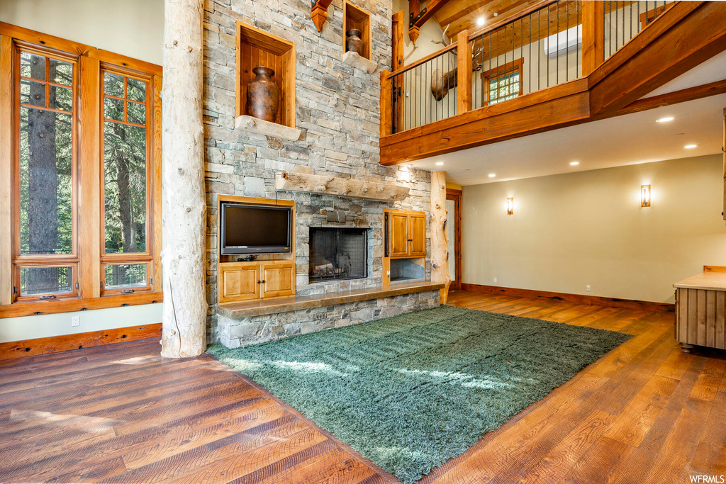 Hardwood floored living room featuring a fireplace and a high ceiling